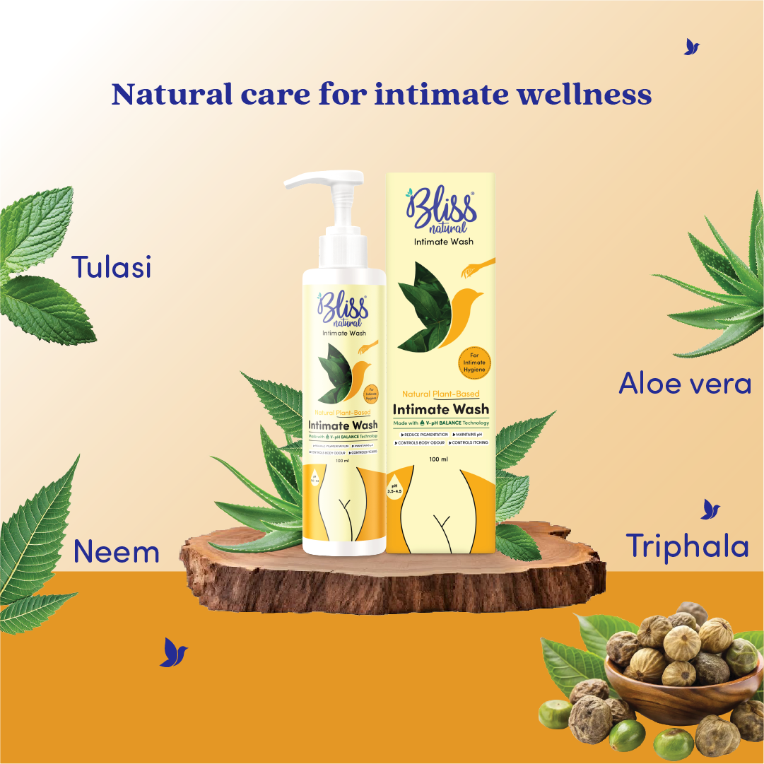 Bliss Intimate Wash bottles with natural ingredients on a wooden platform against a beige background